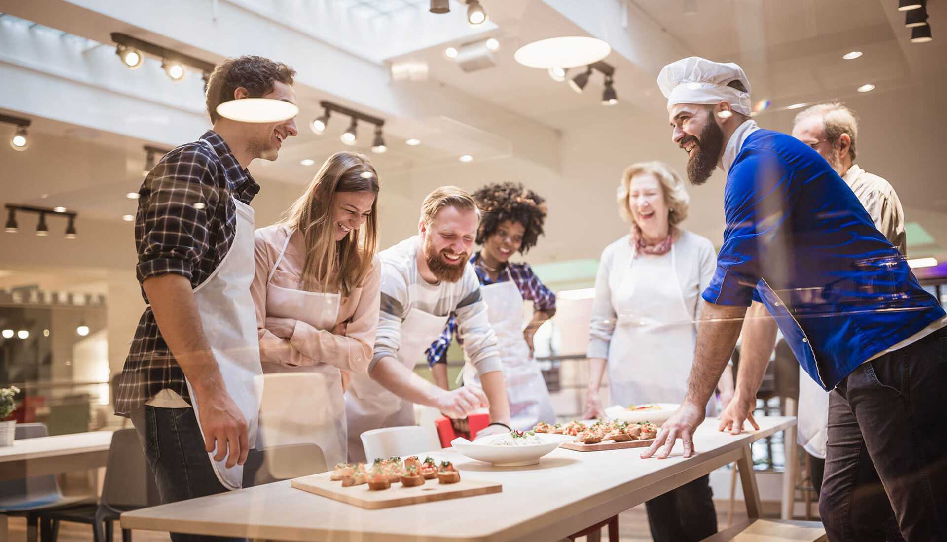 Group of people smiling and standing around a counter preparing food