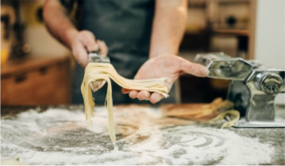 Set of hands making pasta on a bread board