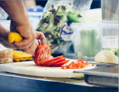 A large tomato being sliced on a bread board